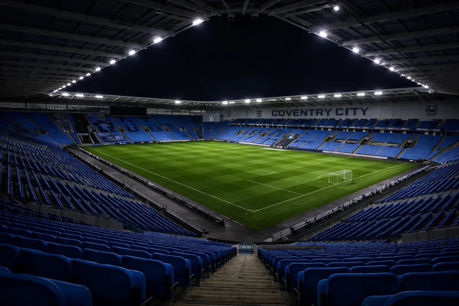Coventry City stadium interior night view with illuminated pitch and empty stands