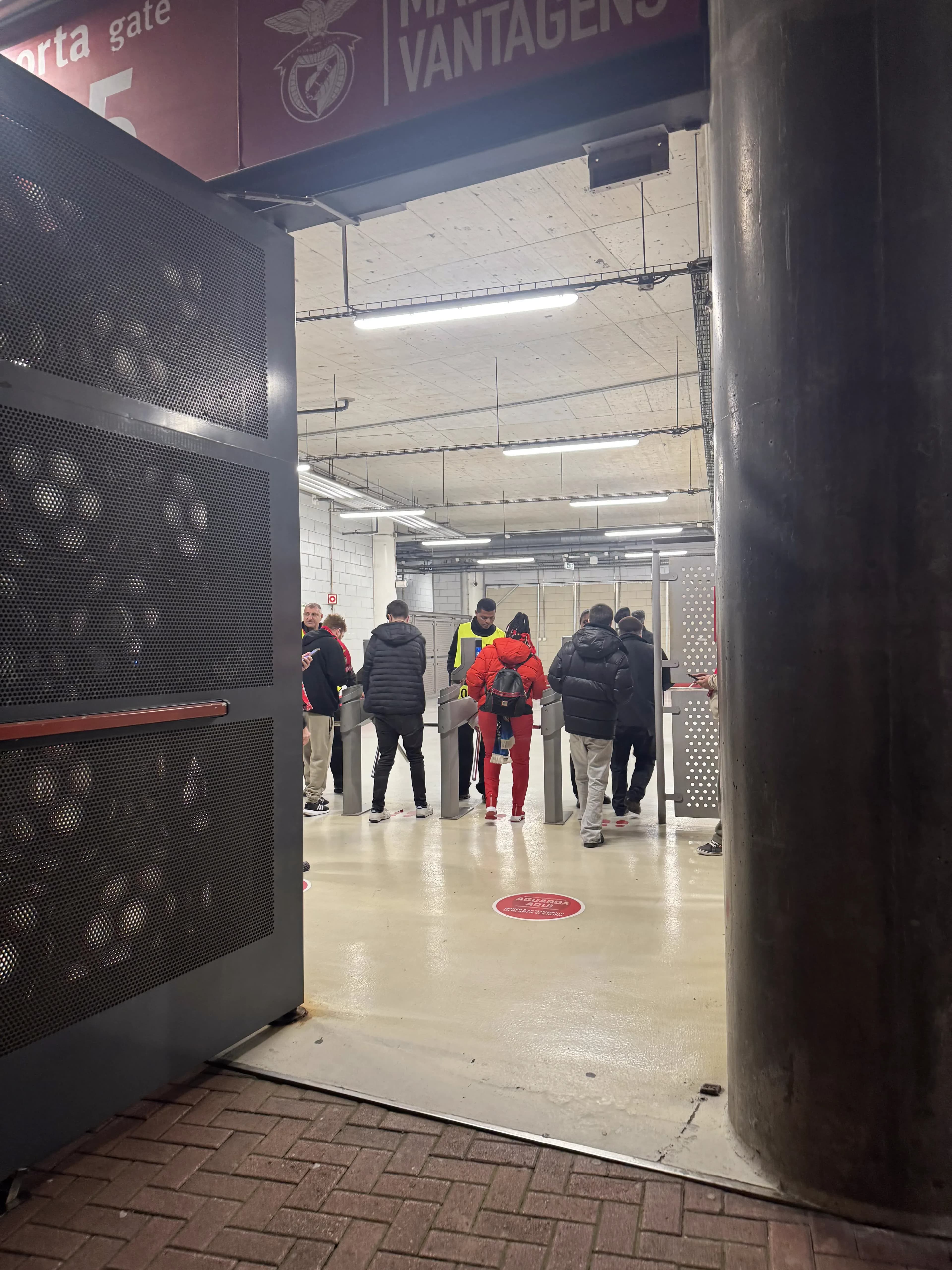 Fans passing through the turnstiles at Gate 5 of Estádio da Luz on matchday, with Benfica branding and security staff visible